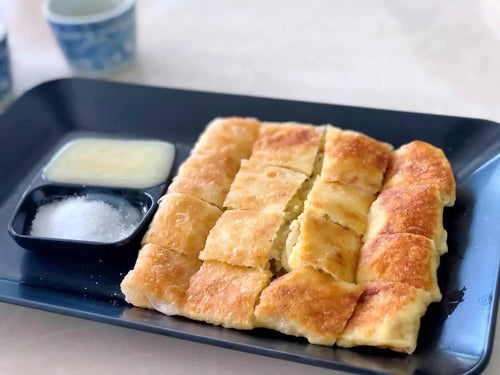 Thai Roti served in a plate with sugar in a small bowl