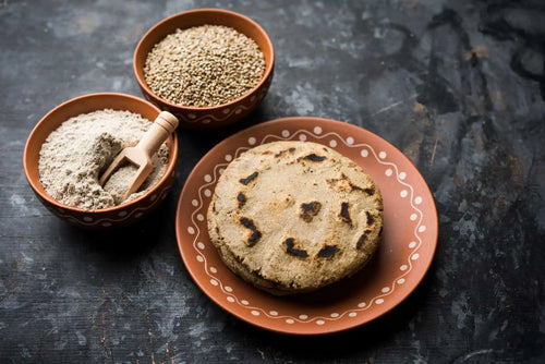 A plate with a Bajra roti, bowl of bajra flour, and bowl of bajra seeds