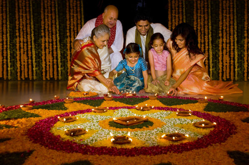 A family lighting a diya in front of a flower arrangement.