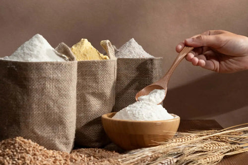 3 different flours placed in sacks and another in a wooden bowl on a table