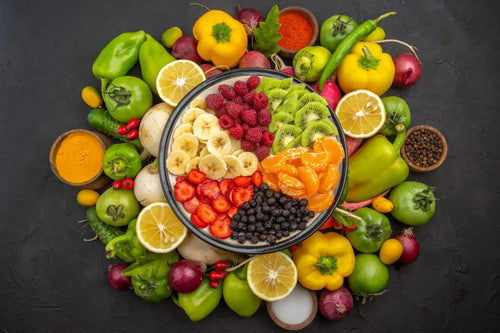 fruits in a bowl with vegetables placed around it